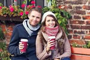 Young couple sitting on bench with coffee photo