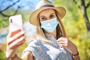 Woman in mask with phone in the park. photo