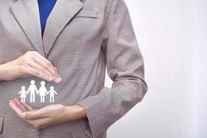 Family in the hands of a businesswoman family protection concept. photo