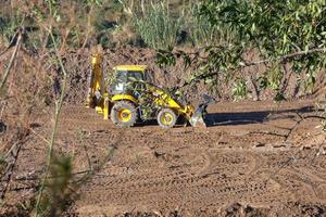 cargadora retroexcavadora de pie en un campo de tierra foto