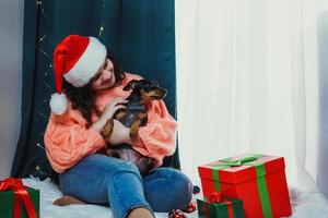 Portrait of young woman playing with funny dog miniature pinscher photo