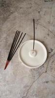 Incense stick in porcelain craft ceramic holder on marble table photo