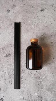 Aromatic reed diffuser bottle with black sticks on a dark marble background. photo