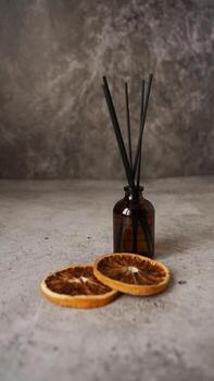 Citrus reed diffuser on dark background. Bottle, sticks and dry oranges photo