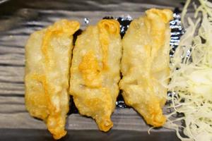 Close-up of golden yellow gyoza placed on black plate with blurred background photo