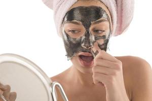 Black facial mask. beautiful girl piling off black mask. beauty concept photo