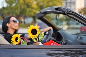 Happy beautiful woman driving a sports car in the city photo