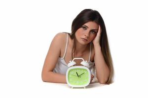 Beautiful sleeping woman resting in bed with alarm clock ready to wake her in the morning. photo