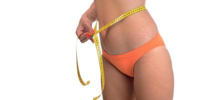 mujer gorda midiendo su línea de cintura con cinta métrica foto