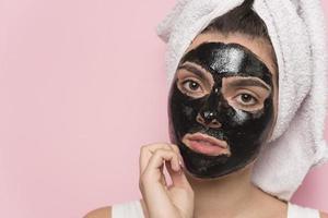 Beautiful smiling woman piling off black cosmetic mask from her face. Beauty concept. isolated photo
