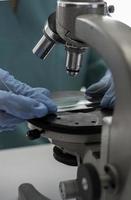 Scientist in blue medical gloves and uniform learning COVID-19 samples with microscope in laboratory. photo