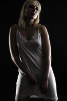 Silhouette of a Beautiful blond woman wearing white nightgown posing on black  background. photo