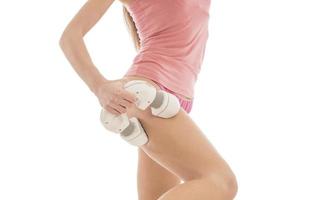 Unknown female with perfect shaped body massaging her legs with electric massager photo