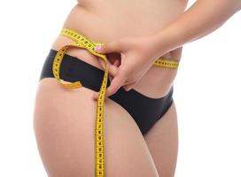 Fat woman measuring her waist line with measuring tape photo