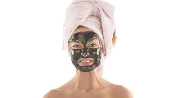 Beautiful girl with black facial cosmetic mask. Beauty concept. isolated photo