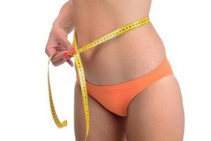 mujer gorda midiendo su línea de cintura con cinta métrica foto