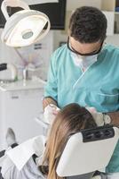 dentista curando los dientes del paciente llenando la cavidad. dentista que trabaja con equipo profesional en la clínica. foto