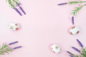 Painted white eggs with gold and lavender, sage flowers on pink background. Happy easter. Copy space photo