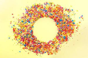 Sweet candy confetti in the middle of a circle with empty space for text. Yellow background photo
