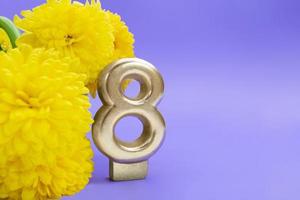 flores amarillas de crisantemo con el número ocho sobre fondo lila. 8 de marzo, día internacional de la mujer, cumpleaños. copie el espacio foto