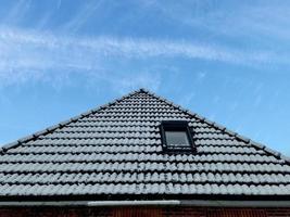 ventana de techo abierta en estilo velux con tejas negras cubiertas de nieve durante el invierno foto