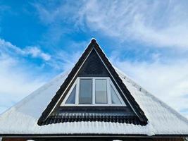 Open roof window in velux style with black roof tiles covered in snow during winter photo