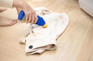 primer plano mano femenina aplicando detergente para eliminar manchas severas en la ropa