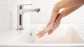 mujer lavándose las manos en el baño de casa foto