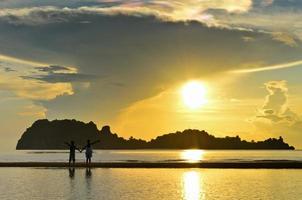 dos niños de pie en la playa viendo el amanecer foto