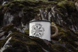 Close up enamel mug with runes on rock concept photo