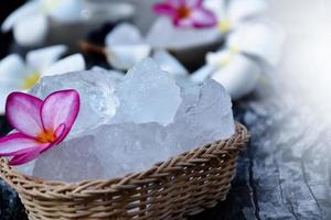 foco suave de cubos de alumbre y flor de plumeria en una pequeña cesta de mimbre, fondo borroso, concepto de hierba, cuidado corporal, cuidado de la piel, agua clara, spa, tratamiento, protección contra enfermedades y proteger el olor de la axila. foto