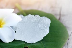 cubos de alumbre sobre maceta de cerámica y fondo de flores de plumeria, concepto de hierba, cuidado corporal, cuidado de la piel, agua clara, spa, tratamiento, protección contra enfermedades y proteger el olor de la axila. foto