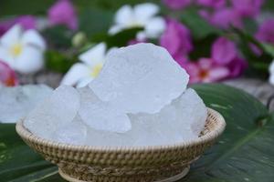 Soft focus of Alum cubes and plumeria flower on small wicker basket, blurred background, concept for herb, bodycare, skincare, waterclear, spa, treatment, disease protection and protect armpit smell. photo