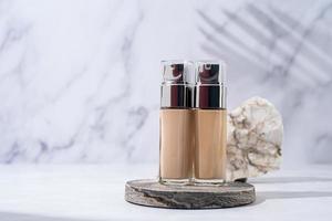 A minimalistic scene of a podium and foundation base bottles with stones on white background, for natural cosmetics photo