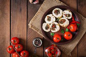 Baked chicken rolls with mushrooms and paprika on brown plate. Top view photo