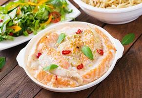 Baked slices of red and white fish with honey and lime juice, served with fresh salad and soft noodles in miso broth photo