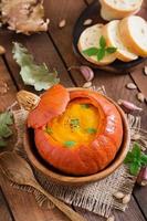 Pumpkin cream soup with peppers and herbs in a pumpkin photo