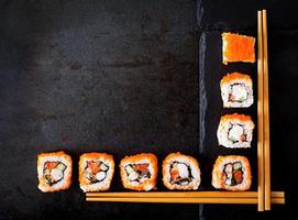Traditional Japanese food - sushi, rolls and chopsticks for sushi on a dark background. Top view photo