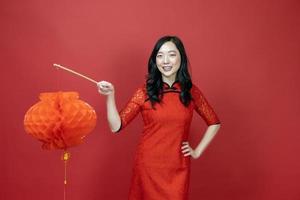 Asian chinese woman in red cheongsam or qipao holding denglong the paper lantern to wish the good luck and prosperity in Chinese New Year celebration holiday isolated on red background photo