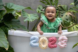 bebé africano sentado en la bañera con el cartel de feliz año nuevo 2023 para la celebración de la temporada para la felicidad y el uso de los niños foto