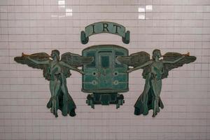 ciudad de nueva york - 20 de abril de 2018 - señal de metro irt new york city en grand army plaza brooklyn, nueva york. dos ángeles tocando la trompeta flanqueando un tren de principios del siglo XX. foto