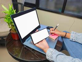 computadora, imagen de maqueta de teléfono de pantalla en blanco con fondo blanco para publicidad, mano de mujer usando computadora portátil y teléfono móvil en la mesa en cafe.mockup foto