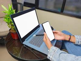 computadora, imagen de maqueta de teléfono de pantalla en blanco con fondo blanco para publicidad, mano de mujer usando computadora portátil y teléfono móvil en la mesa en cafe.mockup foto