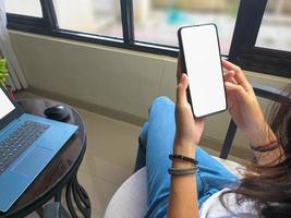 computer, blank screen phone mockup image with white background for advertising, woman's hand using laptop and mobile phone on table in cafe.mockup photo