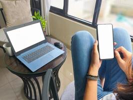 computer, blank screen phone mockup image with white background for advertising, woman's hand using laptop and mobile phone on table in cafe.mockup photo