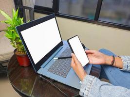 computer, blank screen phone mockup image with white background for advertising, woman's hand using laptop and mobile phone on table in cafe.mockup photo