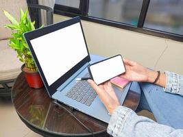 computer, blank screen phone mockup image with white background for advertising, woman's hand using laptop and mobile phone on table in cafe.mockup photo