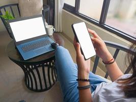 computer, blank screen phone mockup image with white background for advertising, woman's hand using laptop and mobile phone on table in cafe.mockup photo