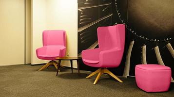 Two Pink wing back chair in modern interior design of Living room. Interior of casual meeting areas in modern corporate office, waiting room or coworking space. Color Of The Year 2023 - Viva Magenta photo