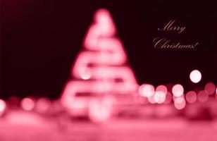 Blurred festive background made with christmas illuminations. Colorful Magenta Christmas tree and Bokeh of the defocused, Bokeh on night background. Color Of The Year 2023 - Viva Magenta photo